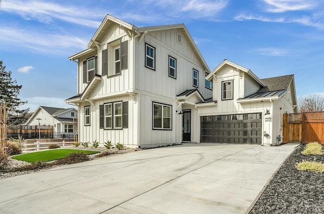 modern inspired farmhouse featuring a garage, fence, concrete driveway, board and batten siding, and a standing seam roof