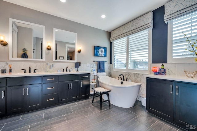 bathroom with a bathtub, vanity, a healthy amount of sunlight, and tile walls