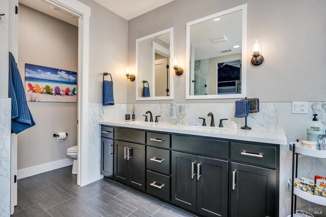 bathroom with vanity, toilet, and tile walls