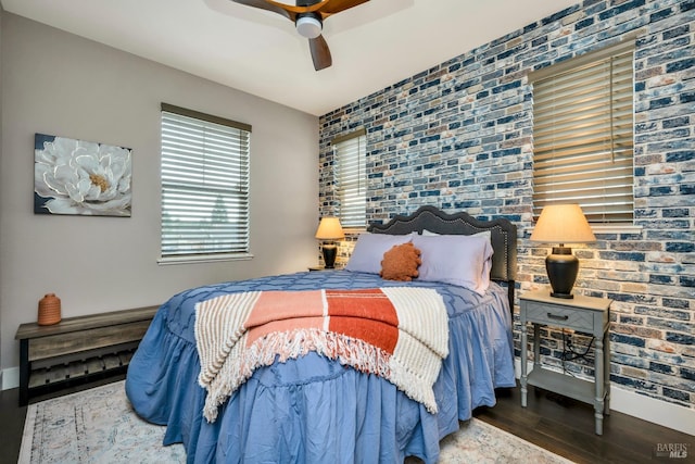 bedroom with hardwood / wood-style flooring, ceiling fan, and brick wall