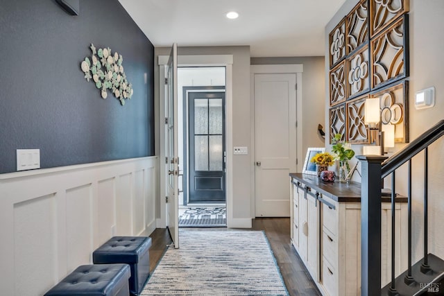 doorway to outside with a wainscoted wall, stairs, and dark wood-style flooring