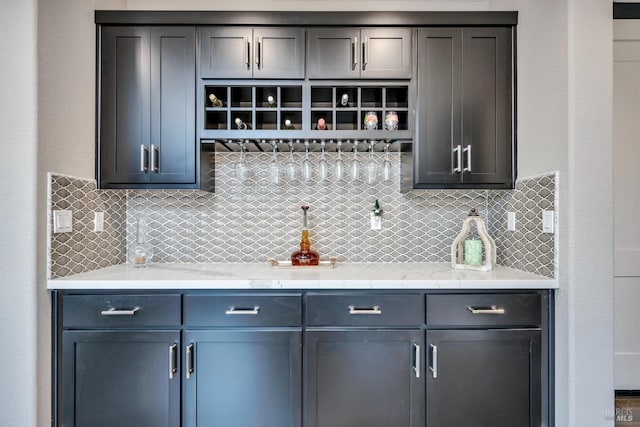 bar featuring light stone countertops and tasteful backsplash