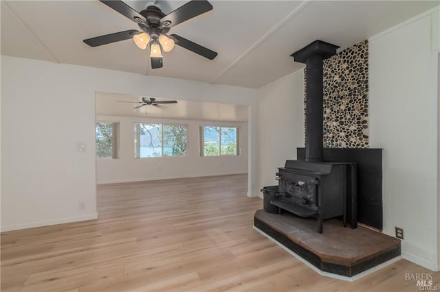 living room featuring light wood-type flooring, ceiling fan, and a wood stove