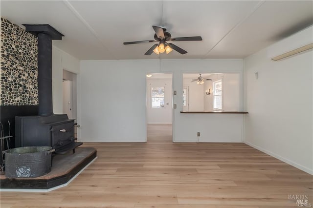 living room featuring light hardwood / wood-style flooring, ceiling fan, and a wood stove