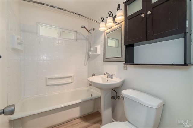 bathroom with tiled shower / bath, toilet, and wood-type flooring