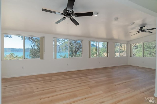 unfurnished sunroom featuring lofted ceiling, plenty of natural light, ceiling fan, and a water view