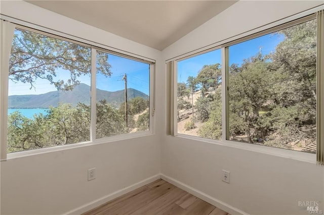 unfurnished sunroom featuring vaulted ceiling and a water and mountain view