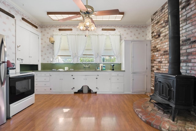 kitchen with light hardwood / wood-style flooring, electric range, a wood stove, white cabinetry, and ceiling fan