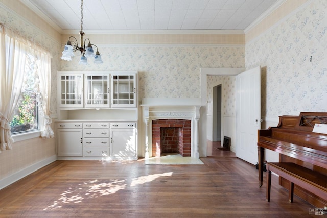 living room featuring crown molding, wood-type flooring, a brick fireplace, and a chandelier