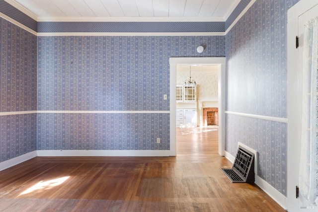 empty room with ornamental molding, hardwood / wood-style flooring, and an inviting chandelier