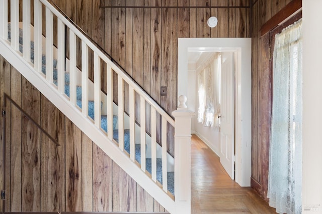 stairway featuring hardwood / wood-style flooring and wooden walls