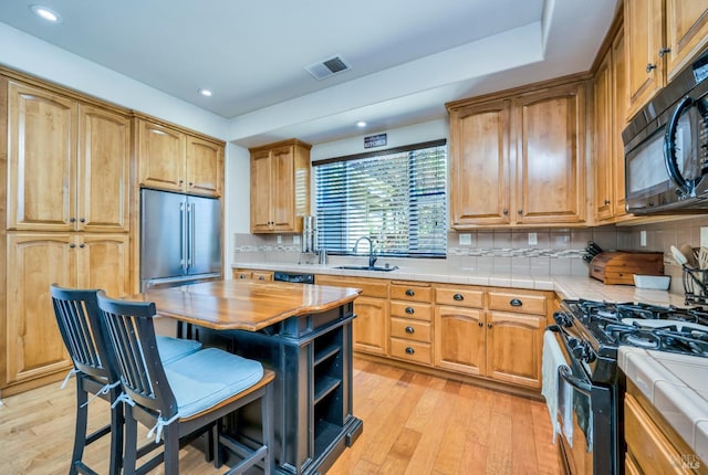 kitchen featuring black appliances, decorative backsplash, sink, and tile countertops