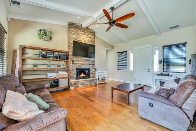 living room featuring ceiling fan, lofted ceiling with beams, a fireplace, and light hardwood / wood-style flooring