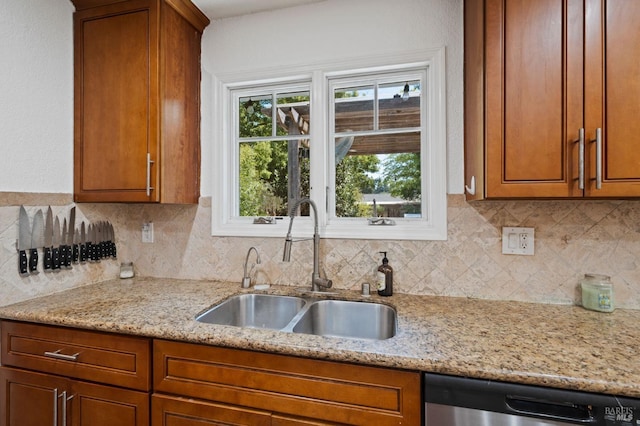 kitchen featuring dishwasher, brown cabinetry, tasteful backsplash, and a sink