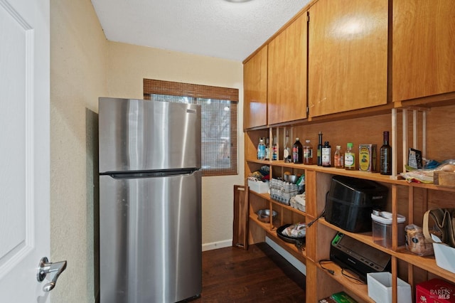 kitchen featuring dark wood-style floors, baseboards, freestanding refrigerator, and a textured ceiling