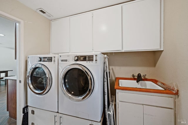 washroom with visible vents, cabinet space, independent washer and dryer, and a sink