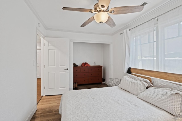 bedroom with baseboards, wood finished floors, visible vents, and ornamental molding