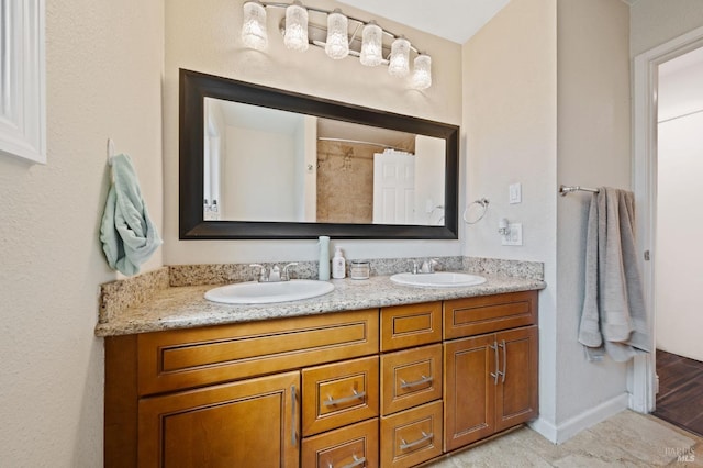 full bath with double vanity, baseboards, and a sink