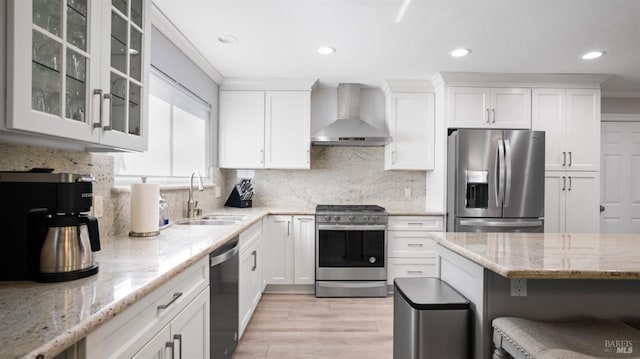 kitchen featuring wall chimney exhaust hood, appliances with stainless steel finishes, a sink, and white cabinetry