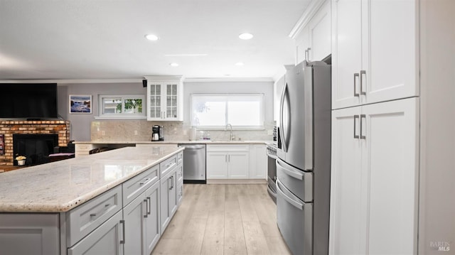 kitchen with backsplash, appliances with stainless steel finishes, glass insert cabinets, ornamental molding, and a sink