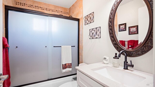 full bathroom with toilet, vanity, and bath / shower combo with glass door