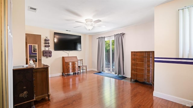 living room featuring baseboards, visible vents, ceiling fan, and wood finished floors