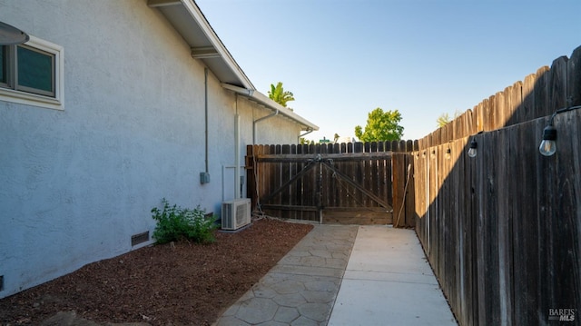 view of side of property featuring crawl space, a gate, fence, and stucco siding