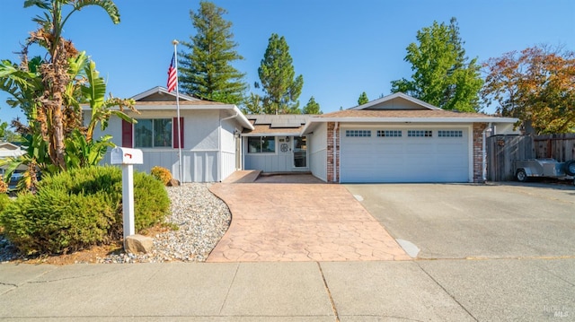 single story home featuring an attached garage, driveway, fence, and solar panels