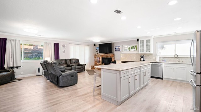 kitchen with appliances with stainless steel finishes, a center island, a brick fireplace, and white cabinets