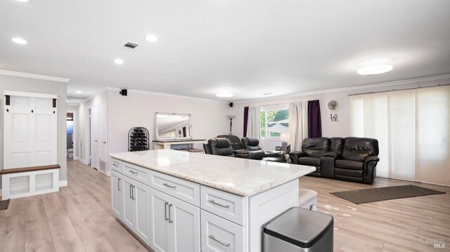 kitchen featuring light stone counters, ornamental molding, white cabinets, and light wood-type flooring