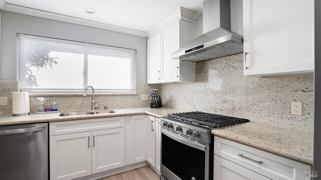 kitchen featuring sink, white cabinets, decorative backsplash, stainless steel appliances, and wall chimney range hood