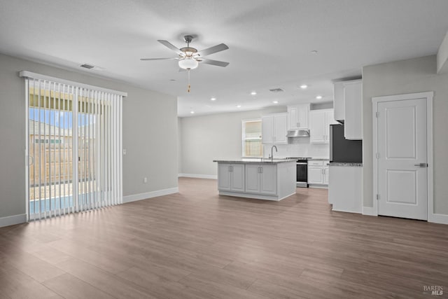 kitchen with stainless steel appliances, wood finished floors, visible vents, white cabinetry, and backsplash