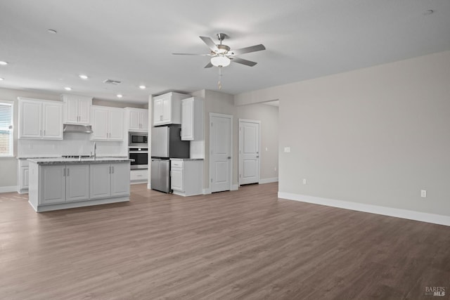 kitchen with tasteful backsplash, appliances with stainless steel finishes, white cabinets, light stone countertops, and exhaust hood