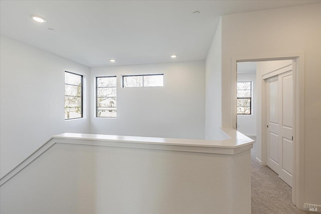 hall with a wealth of natural light and light carpet