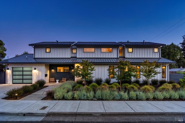 view of front of home with metal roof, an attached garage, concrete driveway, board and batten siding, and a standing seam roof