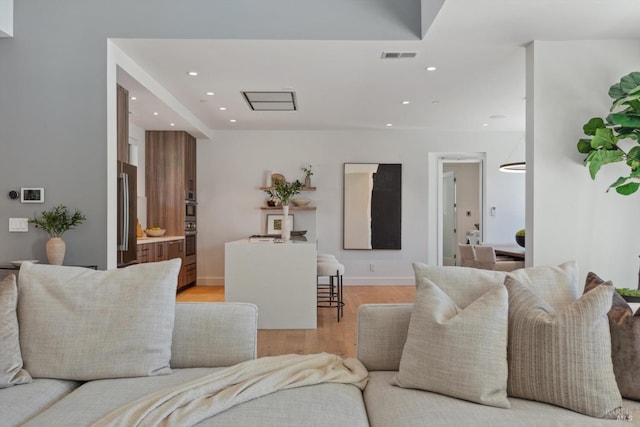 living room featuring light wood-style flooring, visible vents, baseboards, and recessed lighting