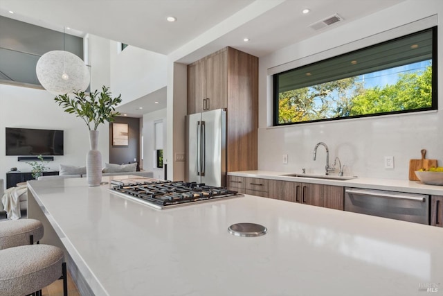 kitchen featuring appliances with stainless steel finishes, brown cabinets, a sink, and modern cabinets