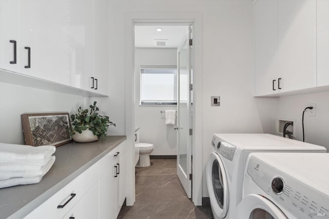 clothes washing area featuring independent washer and dryer, cabinet space, visible vents, and baseboards