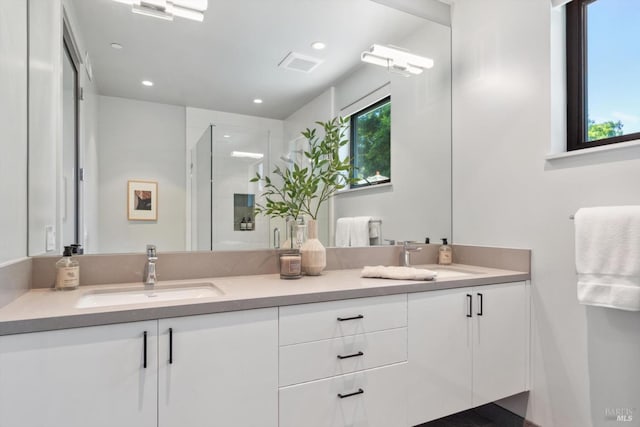 full bath featuring double vanity, a stall shower, visible vents, and a sink