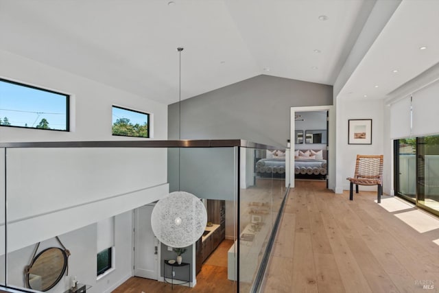 hallway with lofted ceiling, plenty of natural light, and light wood-style flooring