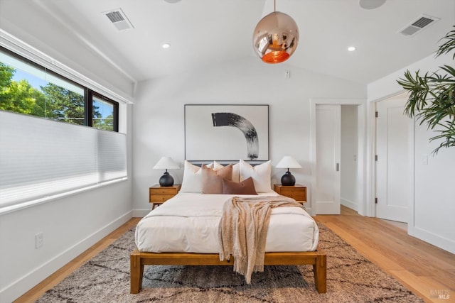 bedroom featuring light wood-type flooring, visible vents, lofted ceiling, and baseboards