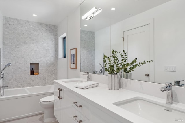 bathroom with double vanity, a tub to relax in, a sink, and toilet