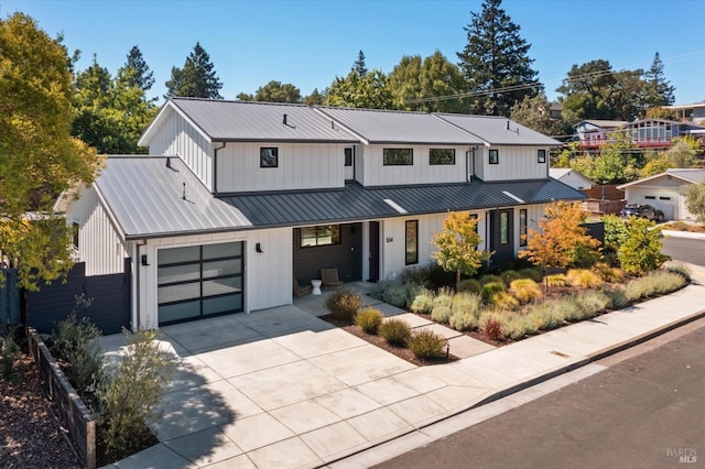 modern farmhouse style home featuring a garage, a standing seam roof, metal roof, and concrete driveway