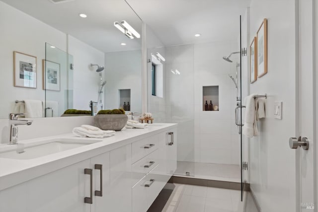 bathroom with double vanity, a stall shower, a sink, and tile patterned floors