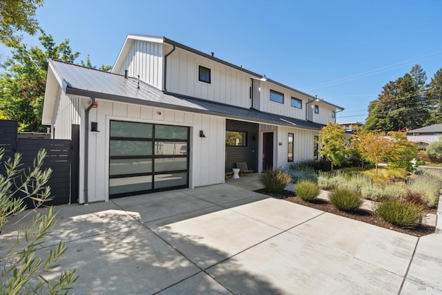 modern farmhouse featuring a standing seam roof, metal roof, fence, concrete driveway, and board and batten siding