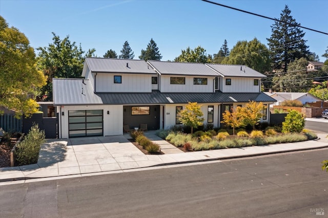 modern inspired farmhouse with a garage, concrete driveway, metal roof, a standing seam roof, and fence