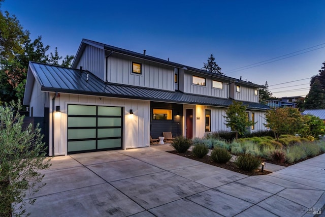 view of front facade with concrete driveway, board and batten siding, a standing seam roof, metal roof, and a garage