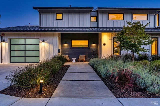 view of front of property with a standing seam roof, driveway, board and batten siding, and a garage