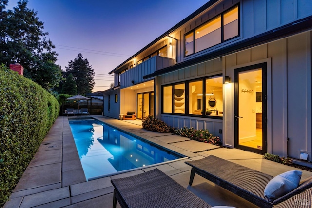 pool at dusk featuring a patio area, a fenced backyard, and an outdoor pool