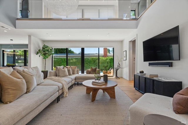 living room with light wood finished floors, a high ceiling, and visible vents